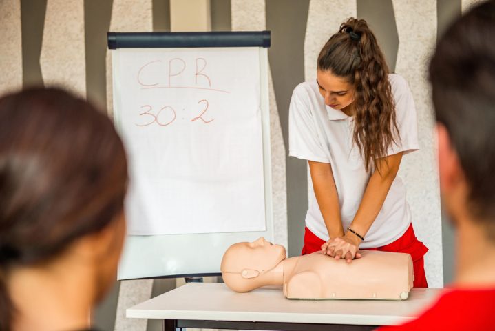 Erste Hilfe Kurs - Frau reanimiert an Puppe