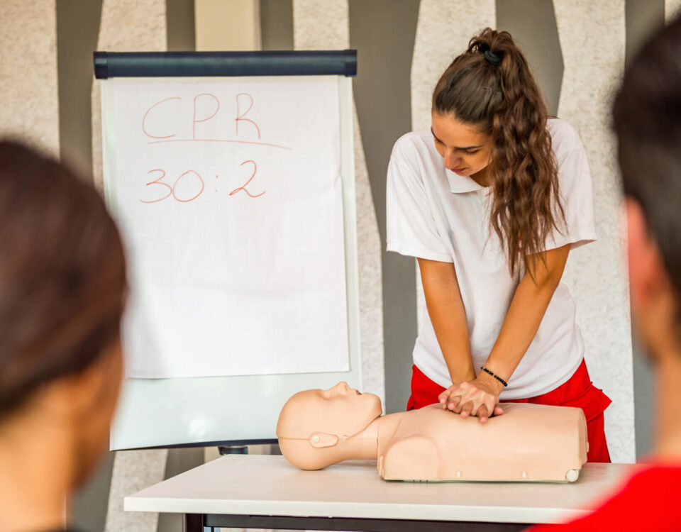 Erste Hilfe Kurs - Frau reanimiert an Puppe
