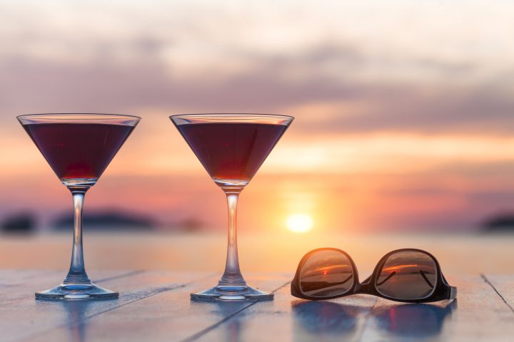 Zweic Cocktails und eine Sonnenbrille vor Sonnenuntergang