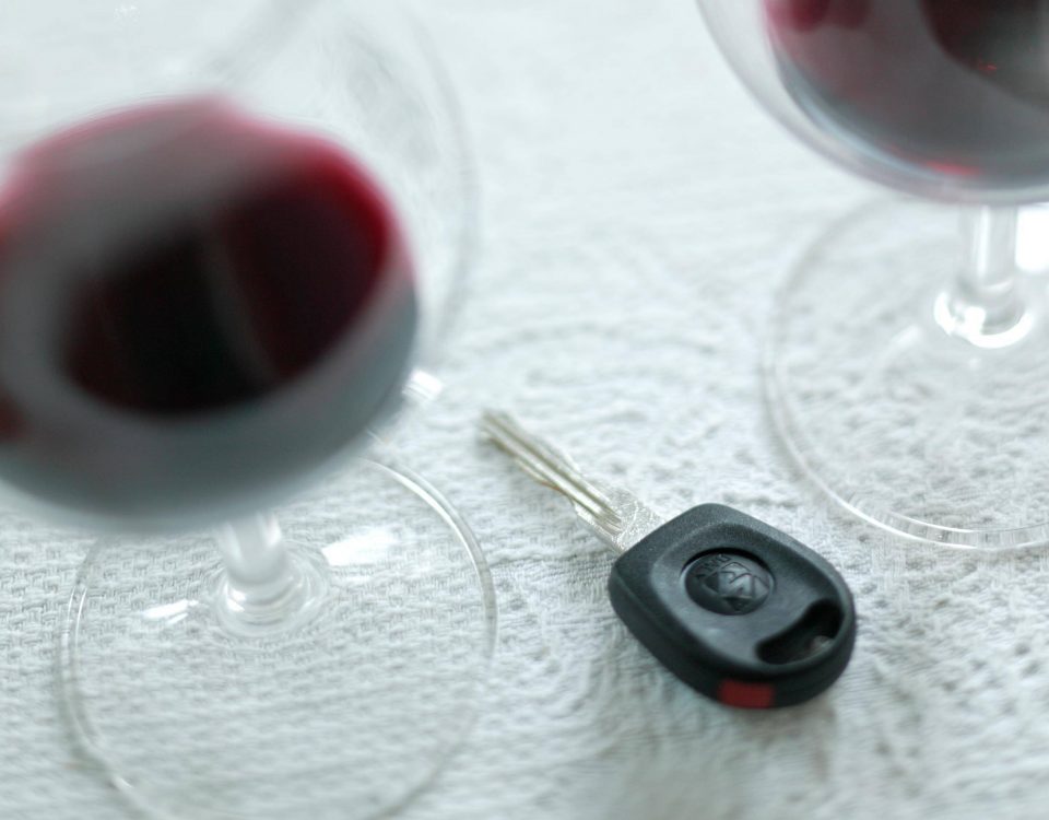 Autoschlüssel neben Gläsern mit Alkohol