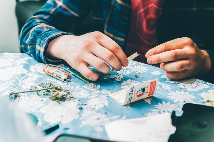 Das Bild zeigt die Hände eines Mannes, die einen Joint drehen.