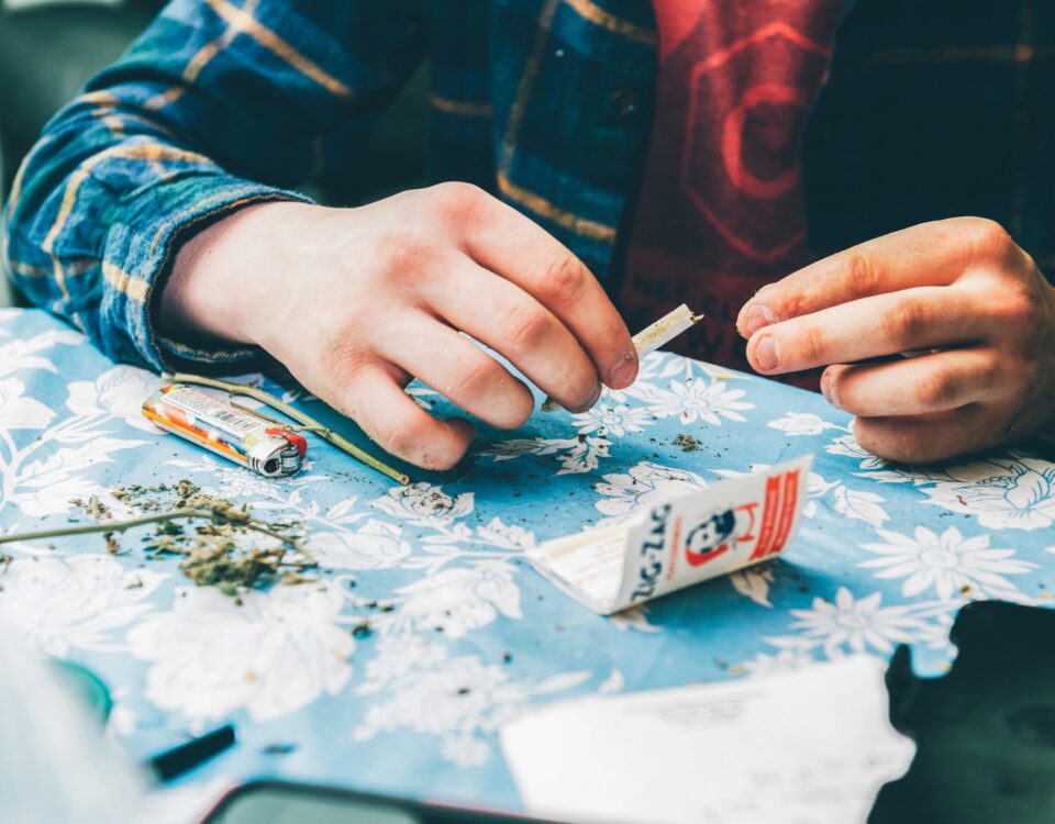 Das Bild zeigt die Hände eines Mannes, die einen Joint drehen.