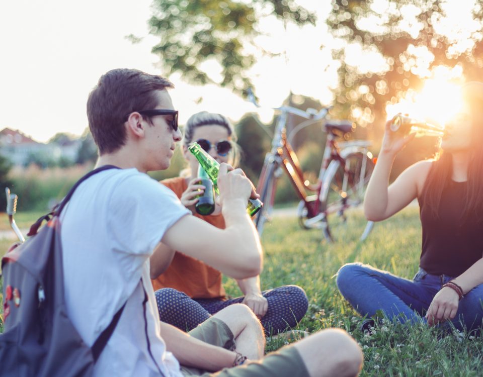 Menschen sitzen im Park und trinken Bier mit einem Fahrrad im Hintergrund