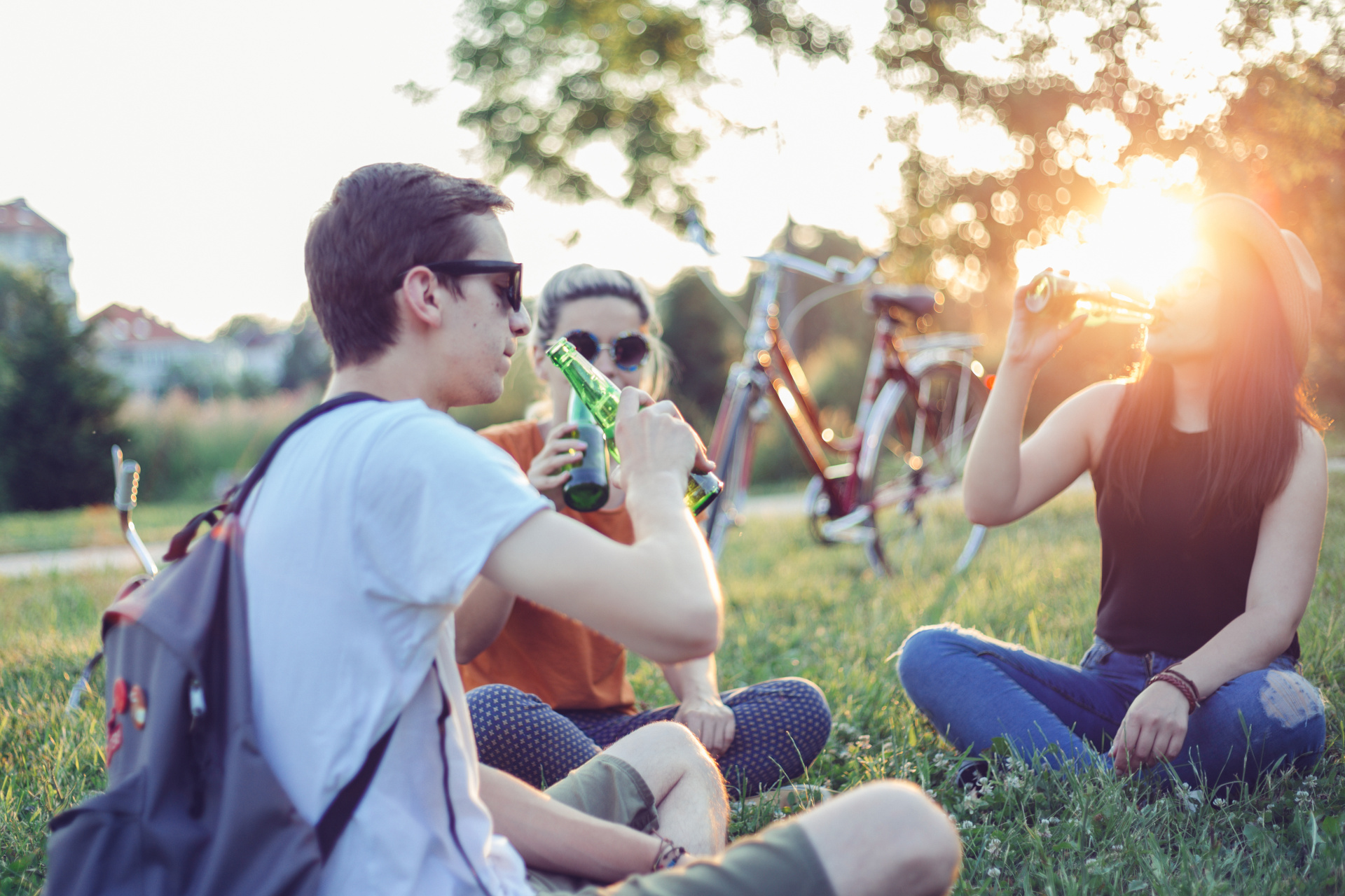 iStock/chabybucko Menschen sitzen im Park und trinken Bier mit einem Fahrrad im Hintergrund