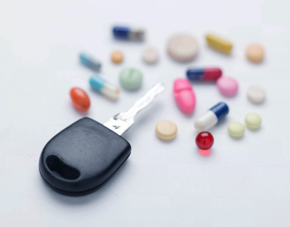Ein Autoschlüssel neben bunten Medikamenten